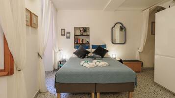 Un dormitorio con cama, mesita de noche, espejo y estantería.