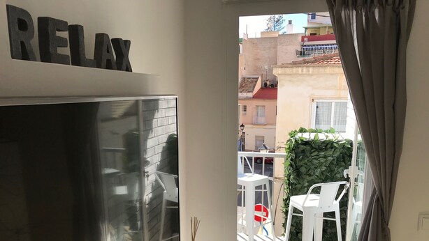 Ein Balkon mit weißen Stühlen, einem kleinen Tisch und einem Topfpflanzen.
