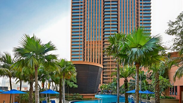 A hotel with a large pool surrounded by palm trees and lounge chairs. - Grand Service Apartment at Times Square (Kuala Lumpur)
