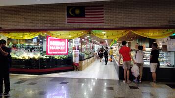 Um mercado com uma placa de destaque HERO MARKET, uma bandeira malaia e piso de azulejos.