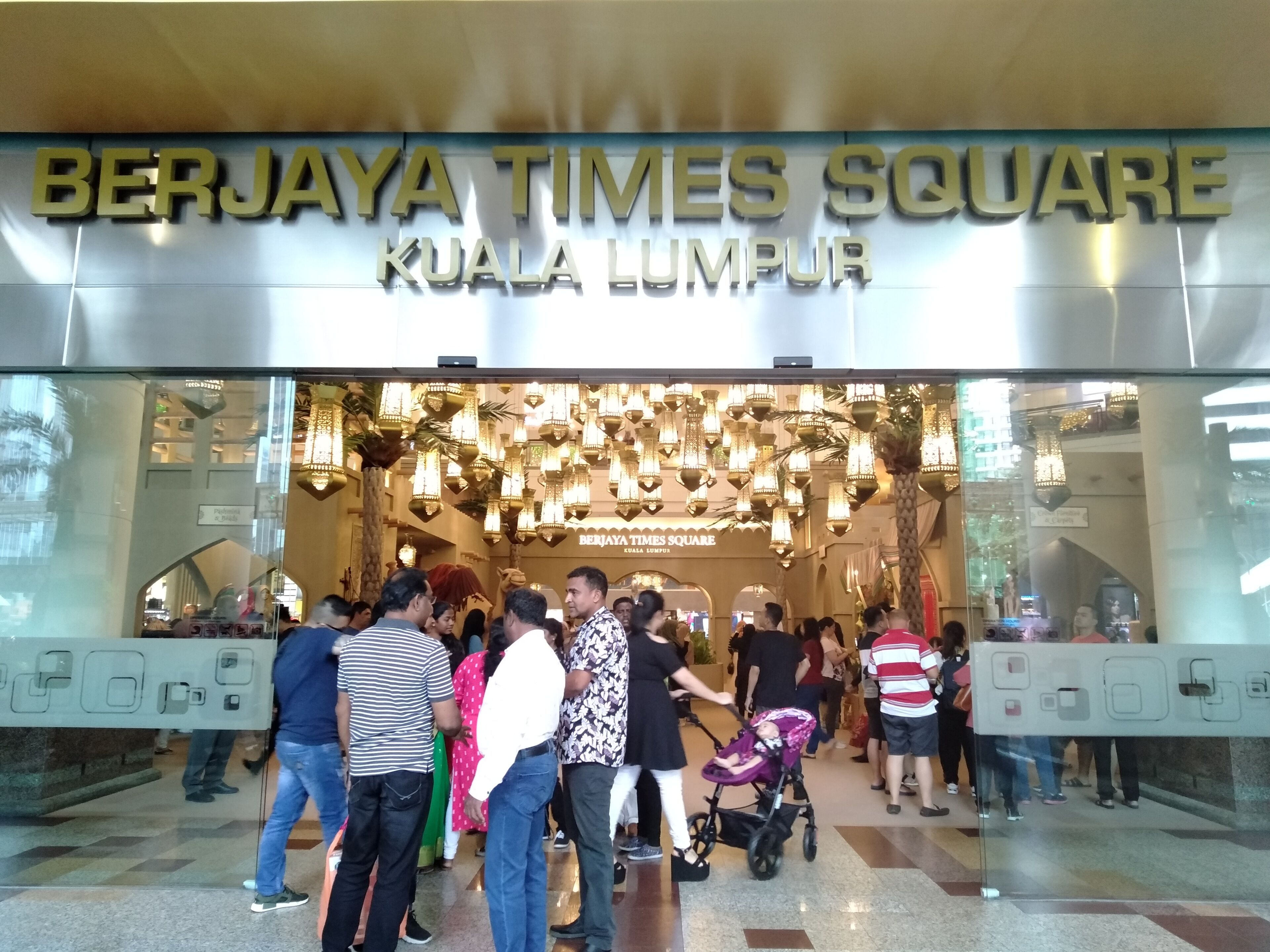 La entrada a Berjaya Times Square en Kuala Lumpur, con una fachada de vidrio moderna y un letrero con letras iluminadas.