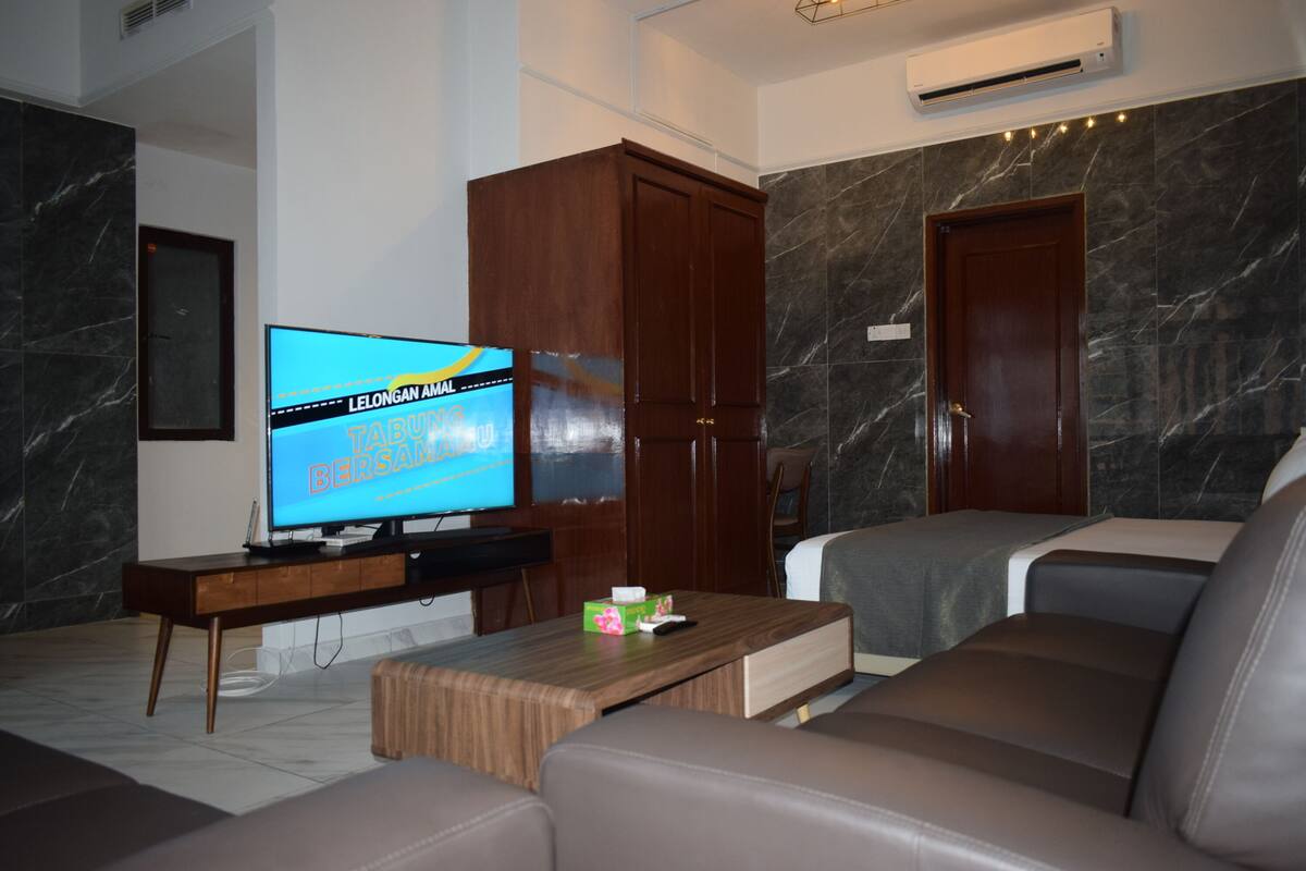 A modern living room with a flat-screen TV, wooden furniture, and a marble wall.
