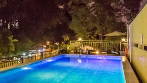 A rectangular swimming pool with clear blue water, surrounded by a low wall and a railing. - Sky View Bed & Breakfast (Yangon)