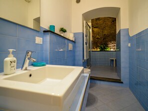 Ein Badezimmer mit einem weißen Waschbecken, blauen Fliesen, einem Spiegel und einer Duschkabine.