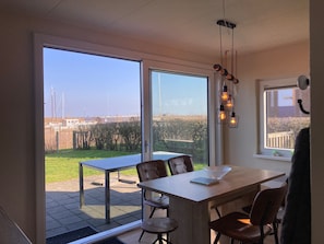 A modern kitchen with large windows, a dining area with a table and chairs, and a view of the outside.