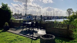 A patio with outdoor seating, a fire pit, and a view of a marina with numerous boats. - Chalet Gaby with sauna, private dock, and canoes at Lauwersmeer (Anjum)