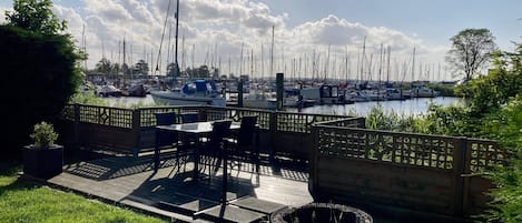 A patio with outdoor seating, a fire pit, and a view of a marina with numerous boats.