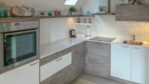 A modern kitchen with a built-in oven, a kettle, and a sink. - Charming Bungalow Rental in Anjum with River Views (Anjum)