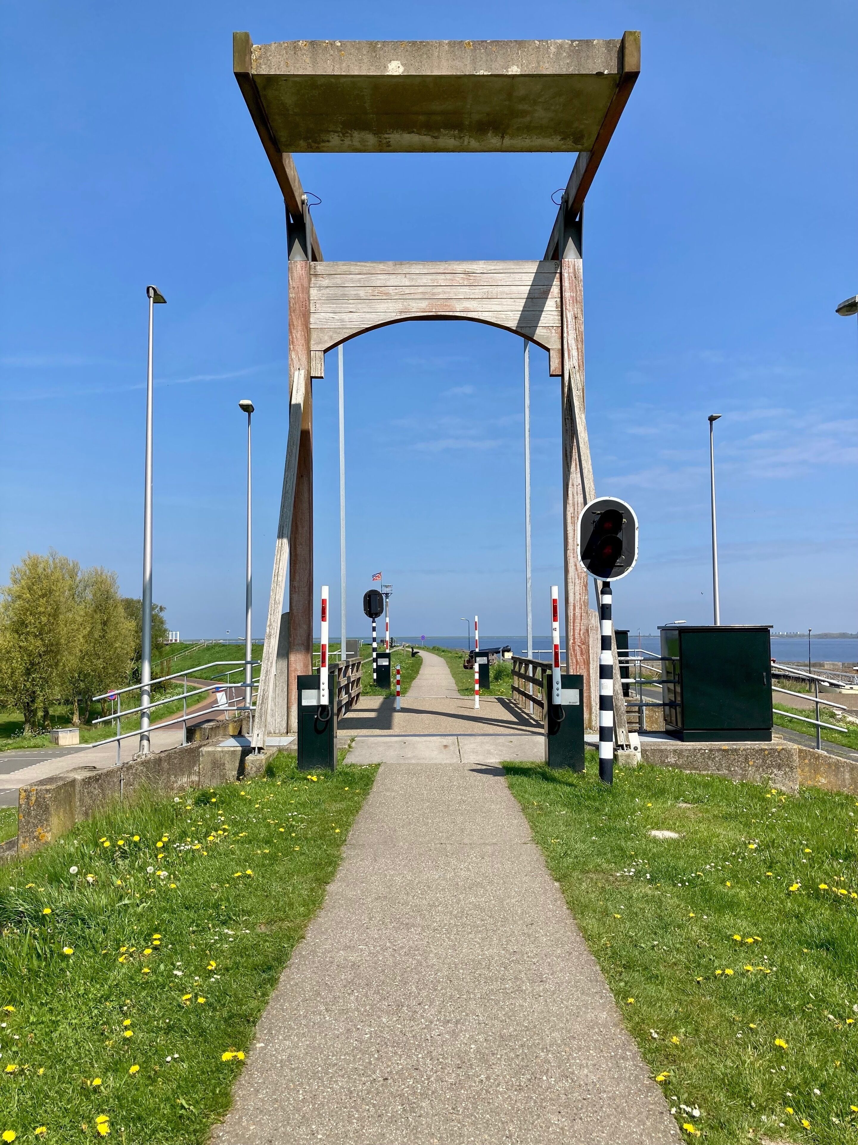 A pedestrian bridge with a metal railing, a pathway, and a clear view of the sea.
