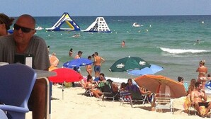 Een strand met mensen, parasols en een glijbaan.