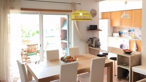 Una cocina luminosa con armarios de madera, una mesa de comedor con sillas y una lámpara colgante amarilla.