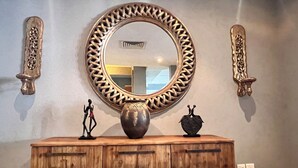 Une coiffeuse en bois, dotée d’un grand miroir, de vases décoratifs et de sculptures murales.
