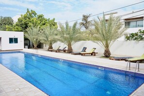 Relax by the pool surrounded by lush palm trees and comfortable lounge chairs.