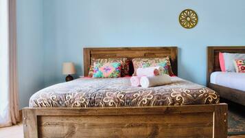 Una cama de madera con ropa de cama estampada, una lámpara de noche y un adorno en la pared.