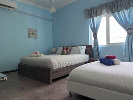 A bedroom with two beds, a bedside table, a lamp, and a window with curtains.