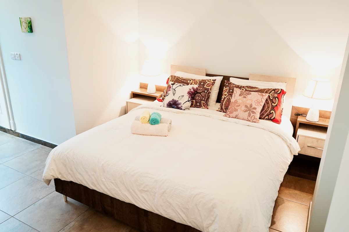 A neatly made bed with a white comforter, two pillows with floral patterns, and a small decorative item on the bed.