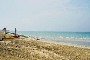 A beach with a sandy shore, a flag, and some equipment.
