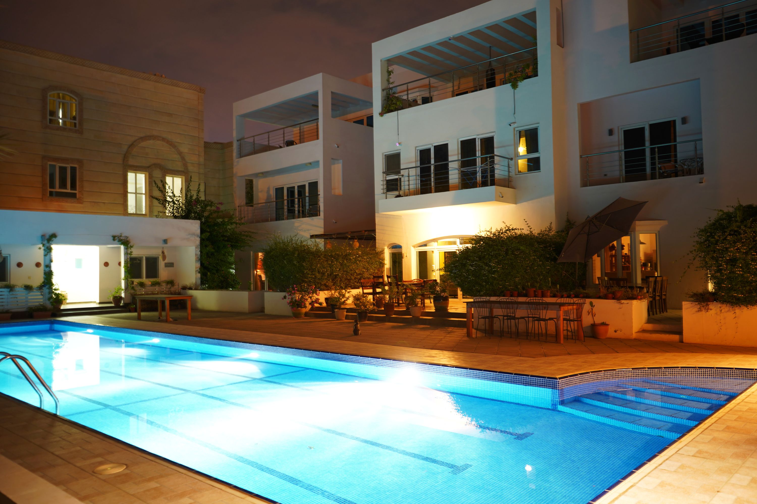 A swimming pool surrounded by a building with multiple balconies and outdoor seating areas.