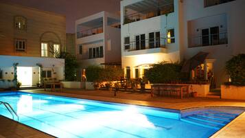 A swimming pool surrounded by a building with multiple balconies and outdoor seating areas.