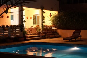 A swimming pool with a wooden deck, a lounge chair, and potted plants. - Behlys Boutique (Muscat)