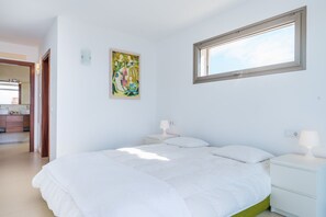 Ein Schlafzimmer mit einem Bett, Nachttischen, einem Fenster und einem Gemälde an der Wand.