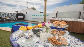 Ein Frühstückstisch am Pool mit Getränken und Gebäck.