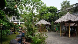A courtyard with thatched-roof structures, a water feature, and lush greenery. - Mandala Hotel (Tangerang)