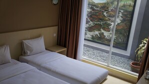 A hotel room with two beds, a large window with a view of a landscape, and a potted plant on the windowsill. - Mandala Hotel (Tangerang)