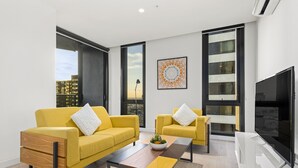 Ein modernes Wohnzimmer mit zwei gelben Sofas, einem Holztisch und einem Flachbildfernseher.