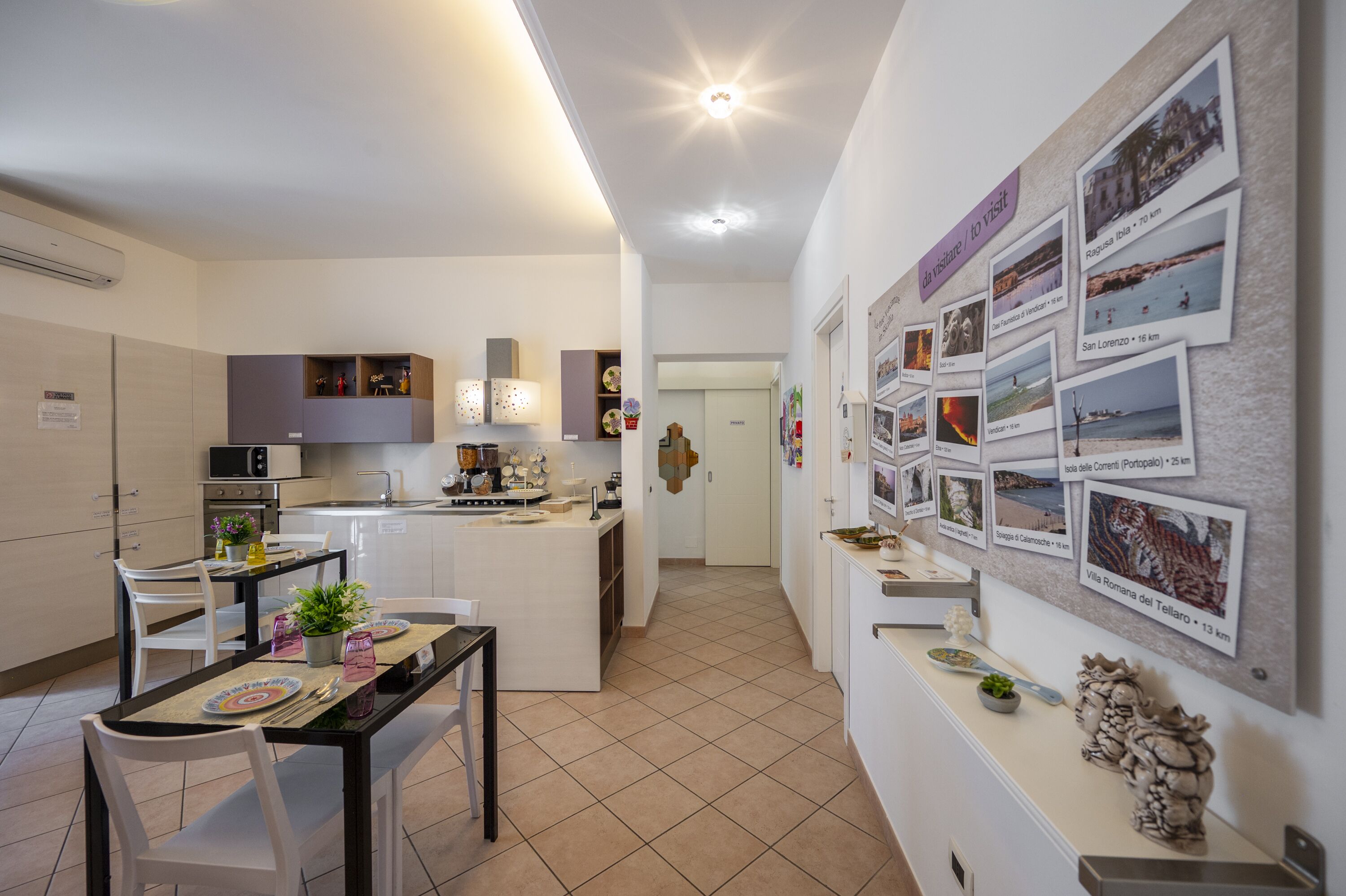 Une cuisine moderne avec des meubles blancs, un îlot central et un coin repas avec une table dressée pour deux personnes.