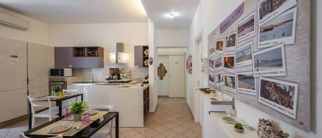 Une cuisine moderne avec des meubles blancs, un îlot central et un coin repas avec une table dressée pour deux personnes.