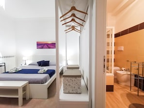 A hotel room with a bed, bedside table, and a bathroom with a toilet and shower.