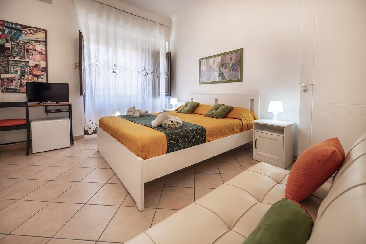 Ein Schlafzimmer mit einem Bett, einem Fernseher, einem Schreibtisch und einer Couch.