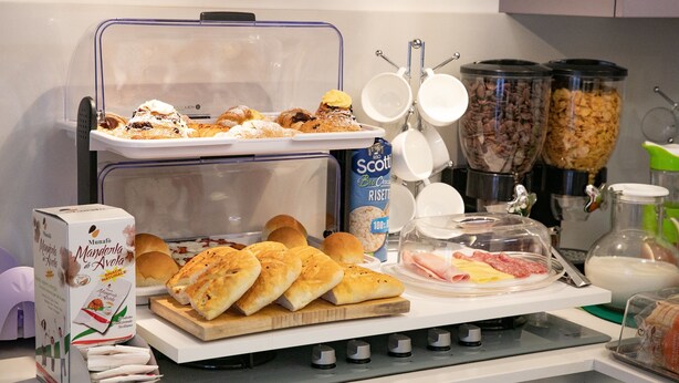 Ein Frühstücksbuffet mit verschiedenen Backwaren, Brot und einer Kaffeestation.