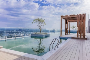 A rooftop infinity pool with a wooden pergola and a tree planter, overlooking a cityscape. - 3BRs Luxury Apartment Cityview (Ho Chi Minh City)