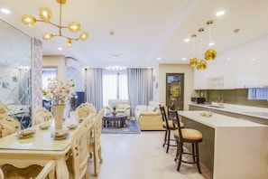 A modern living room with a dining area, a kitchen, and a large window with curtains. - 3BRs Luxury Apartment Cityview (Ho Chi Minh City)