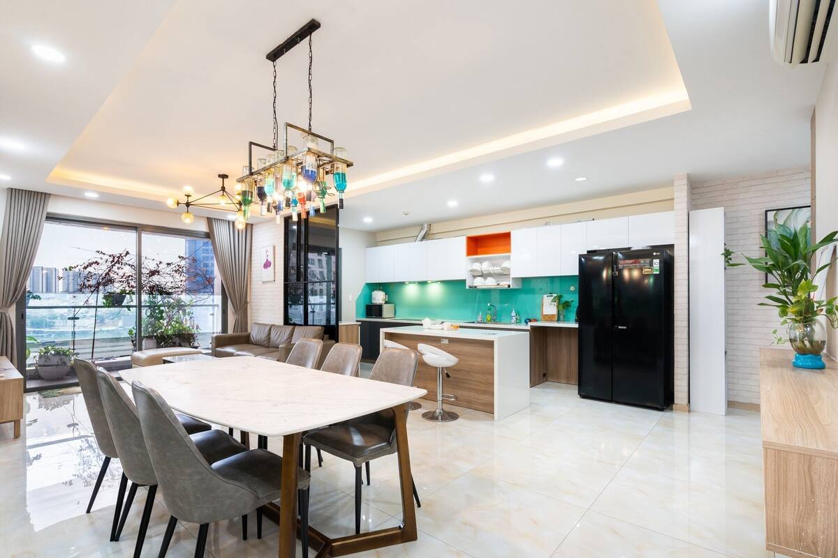 A modern kitchen with a black refrigerator, a teal backsplash, and a dining area with a large table and chairs.