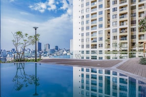 A modern building with a rooftop pool, surrounded by greenery and a city skyline in the background. - 3BRs Luxury Apartment Cityview (Ho Chi Minh City)