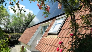 A house with a sloped roof, a visible window, and a pathway leading to the entrance.