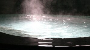 A hot tub with steam rising from the water, surrounded by tiled walls. - Nakajimaya Ryokan (Nozawaonsen)