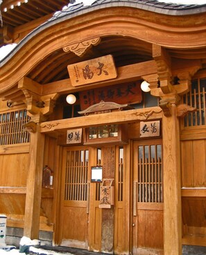A traditional wooden building with a curved roof and multiple signs with Chinese characters.