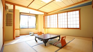 A traditional Japanese room with tatami flooring, a low table, and sliding doors. - Nakajimaya Ryokan (Nozawaonsen)