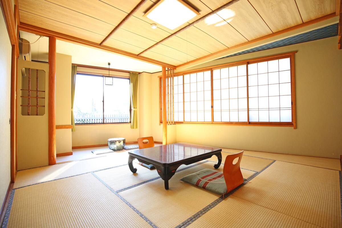Una habitación japonesa tradicional con suelo de tatami, una mesa baja y puertas correderas.