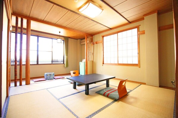 A traditional Japanese room with tatami flooring, a low table, and sliding doors.