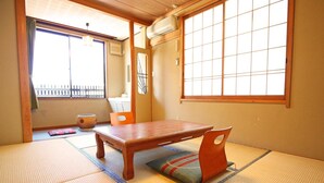A tatami mat room with a wooden table and chairs, large windows, and a sliding door. - Nakajimaya Ryokan (Nozawaonsen)