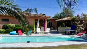 Une piscine avec des chaises longues et une maison en arrière-plan.