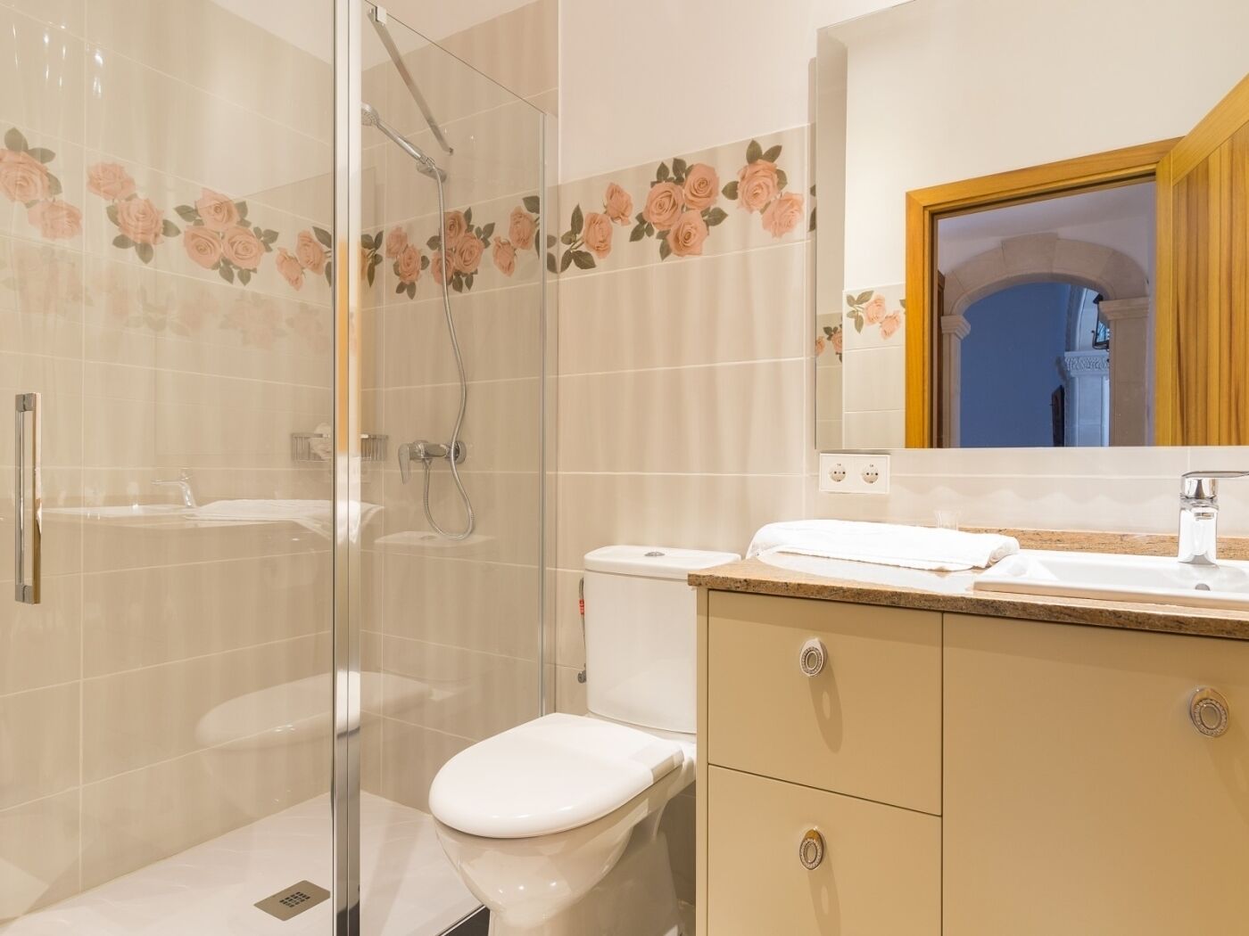 A modern bathroom with a glass shower enclosure, a toilet, and a vanity with a mirror.