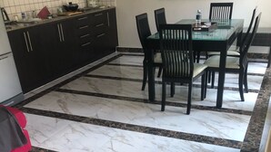 A kitchen with a marble floor, black cabinets, and a dining area with chairs and a table. - Nice Villa in Hua Hin (Hua Hin)