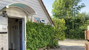 Une maison avec une porte de garage ouverte, un mur de briques, une haie verte et une allée pavée.