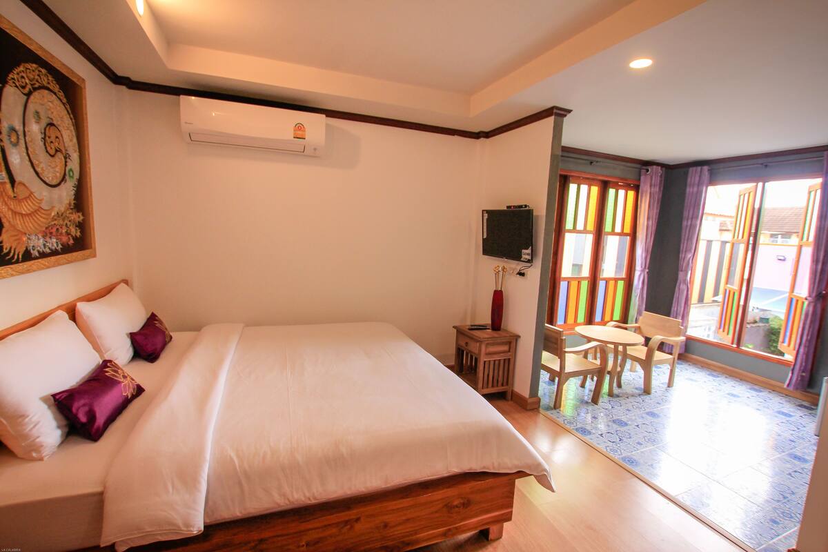 Un dormitorio con cama, televisor y balcón con mesa y sillas.